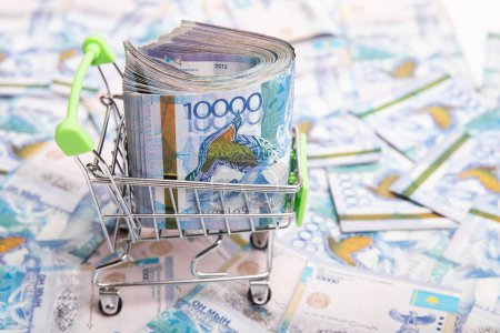 Téléchargez les photos : 10000 Kazakhstan tenge in a shopping cart against the background of Kazakh money. - en image libre de droit