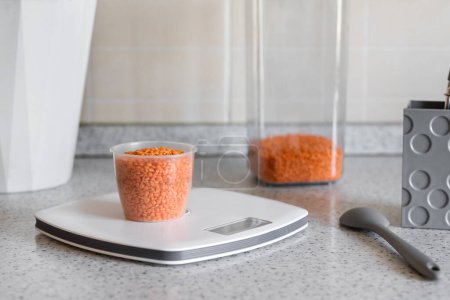 Foto de Escala de cocina con vaso medidor con lentejas rojas en el escritorio de la cocina. Concepto de dieta saludable o dieta para bajar de peso. - Imagen libre de derechos
