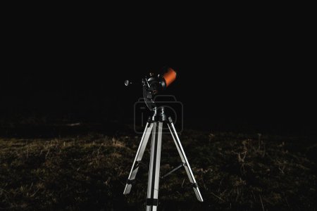 Foto de El telescopio se encuentra en un claro nocturno, listo y configurado para observar las estrellas, copiar espacio. - Imagen libre de derechos