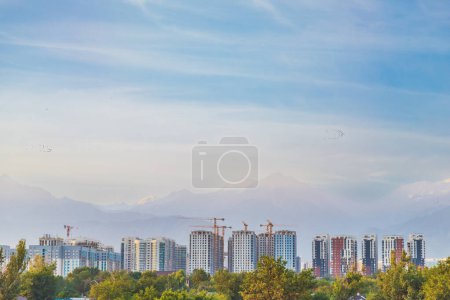Dichte Bebauung der Stadt Almaty mit Wohnhochhäusern vor dem Hintergrund der Berge in einer seismischen Zone, Kopierfläche