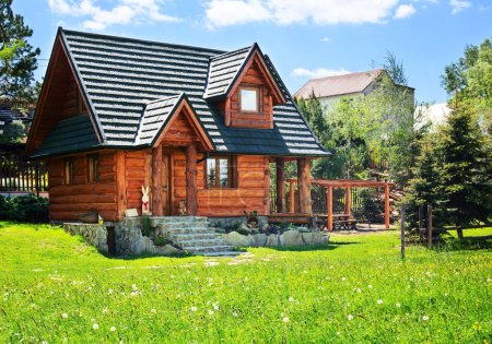 Foto de Hermosa casa de campo de madera moderna con columpio y barbacoa, concepto de descanso vacacional - Imagen libre de derechos