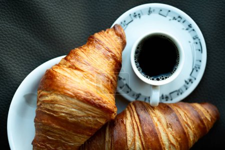 Cup of coffee with two fresh backed croissant