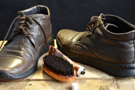 Photo for A pair of leather shoes are on a chair and a shoe brush with cream to clean them. - Royalty Free Image