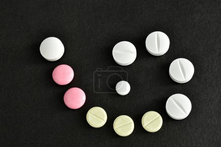 Tablets of different colors and sizes lie in a spiral on a dark table.
