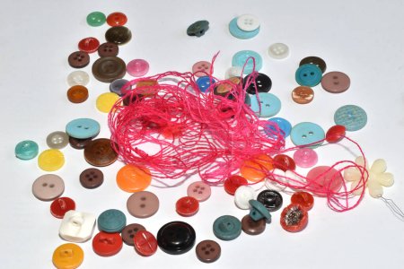 Foto de El patrón de fondo fue creado con botones multicolores e hilo rojo delgado dispersos en la mesa. - Imagen libre de derechos
