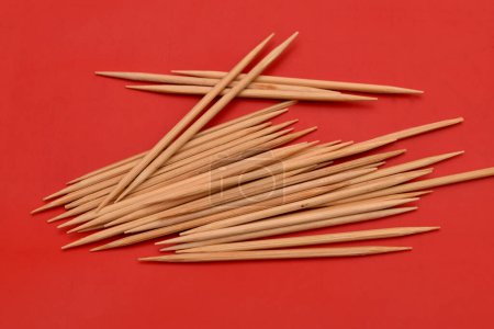 Photo for Bamboo toothpicks lie in a pile on a red background. - Royalty Free Image