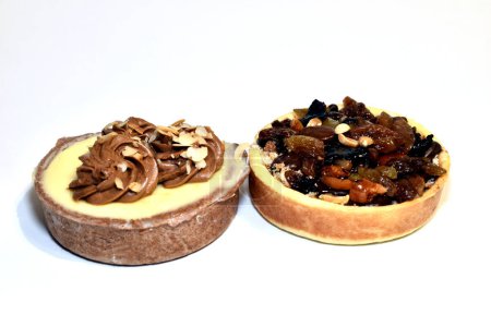 Deux paniers à gâteaux ronds, avec fromage cottage, crème, raisins secs et noix sur fond blanc.