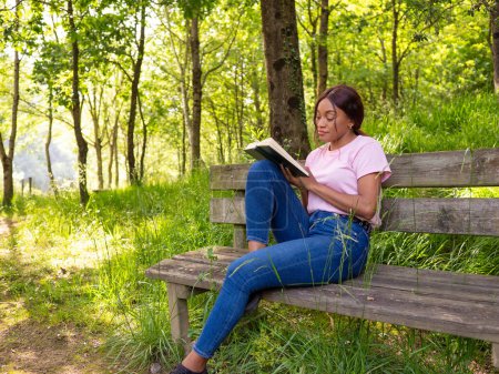 A woman is seated on a bench, engrossed in reading a book.