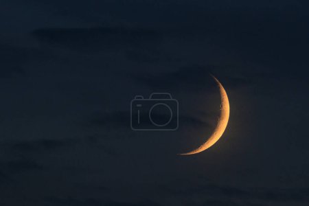 Téléchargez les photos : Isolated young moon crescent highlighted by sun at the evening time. On blue cloudy sky background. Astronomical photography - en image libre de droit