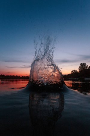 Téléchargez les photos : Splash on a lake water at the sunset time. At the summertime. Reflection on a water surface - en image libre de droit