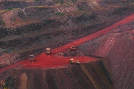 Téléchargez les photos : Bulldozer and couple trucks in quarry with red ground. Mining iron ore in Kriviy Rih, Ukraine. Industrial landscape - en image libre de droit