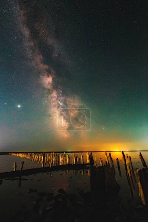 Téléchargez les photos : Bright night landscape with Milky Way galaxy stripe and Jupiter over the salt lake in Henichesk, Ukraine. Atmospheric green air glow effect - en image libre de droit