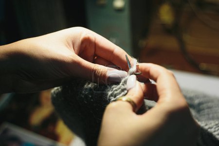 Téléchargez les photos : Close up hands knitting the dress from light wool on blurry background. Using circular needles - en image libre de droit