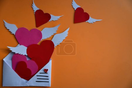 Téléchargez les photos : Enveloppe de courrier blanc remplie de coeurs roses et rouges volant hors de lui sur les ailes de l'amour. concept possible : carte de voeux, déclaration d'amour - en image libre de droit