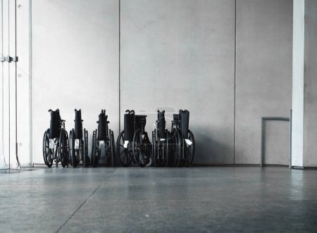 Wheelchair in the building. Disabled carriage equipment standing in the room with concrete background.