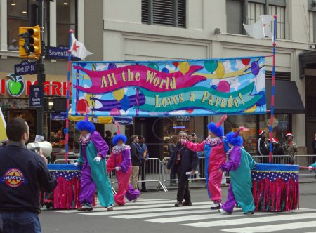 Foto de MACY 'S THANKSGIVING DAY PARADE-NEW YORK CITY, USA-NOVIEMBRE 26, 2015: Una tradición navideña en Nueva York, el desfile es conocido por sus globos gigantes, bandas de marcha y payasos. Aquí vemos payasos y una gran pancarta que dice: "Todo el mundo ama un desfile." - Imagen libre de derechos