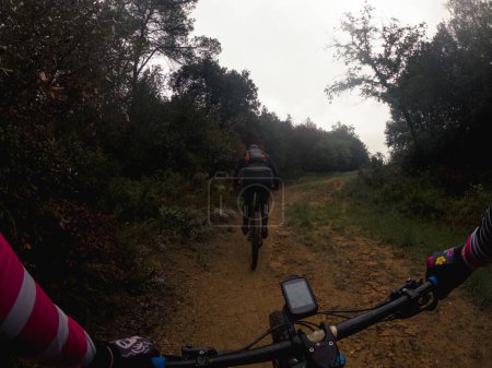 Chasing another rider on a mountain bike race on a muddy forest path
