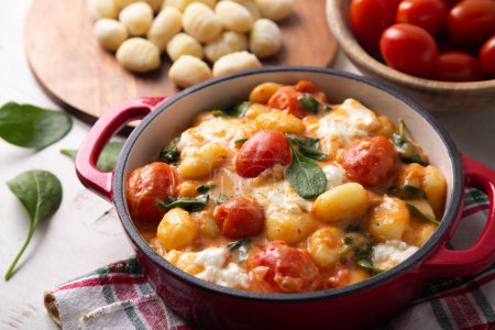 Téléchargez les photos : Gros plan d'une casserole de gnocchi dans une sauce tomate crémeuse aux épinards et à la mozzarella fondue - en image libre de droit