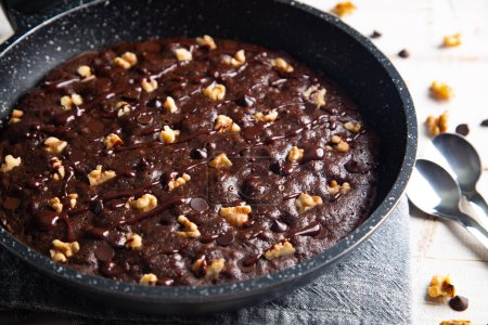 Hausgemachter Brownie gekocht in einer Pfanne, nicht gebacken, mit Nüssen, Schokoladenchips auf einem weißen Tisch