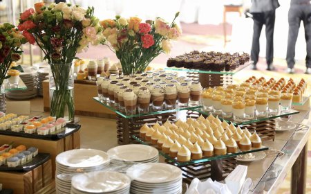 Téléchargez les photos : Une photographie de desserts de boulangerie exposés sur une table avec des gens en arrière-plan. - en image libre de droit