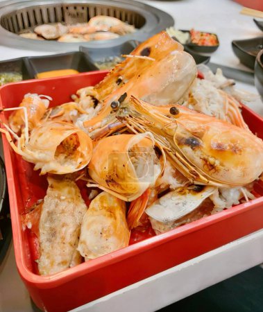 Téléchargez les photos : Une photographie d'un bol rouge rempli de crevettes et d'autres aliments, il y a un récipient rouge rempli de crevettes et d'autres aliments. - en image libre de droit
