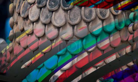 Téléchargez les photos : Une photographie d'un oiseau coloré fait de pièces de monnaie et d'un parapluie arc-en-ciel, des plumes aux couleurs vives sont exposées sur un écran dans un magasin. - en image libre de droit