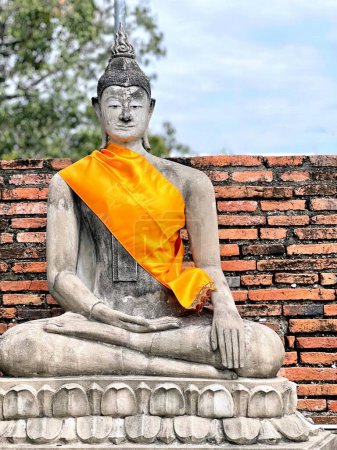 Foto de Una fotografía de una estatua de una persona sentada en una posición de meditación, hay una estatua de un buddha sentado en una plataforma de piedra. - Imagen libre de derechos