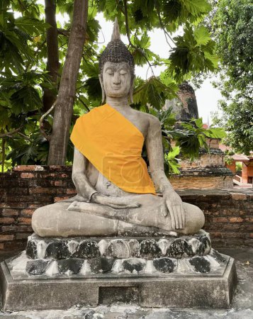 Foto de Una fotografía de una estatua de una persona sentada en una posición de meditación, hay una estatua de una persona sentada en un banco de piedra. - Imagen libre de derechos