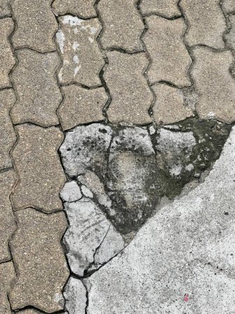 Foto de Una fotografía de una acera rota con un agujero en forma de corazón en el centro, hay un pedazo roto de hormigón en el suelo. - Imagen libre de derechos