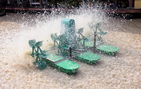 Photo for A photography of a fountain with a green water spouting from it, there are four green lawn chairs in the water splashing. - Royalty Free Image