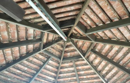 Téléchargez les photos : La photographie du toit avec la structure en bois et la poutre métallique, le toit avec les poutres apparentes et les poutres apparentes en bois. - en image libre de droit