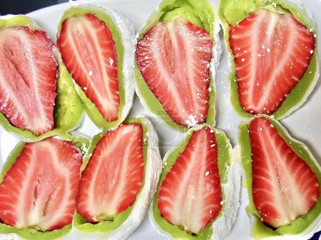 Téléchargez les photos : Une photographie d'une assiette blanche surmontée de fraises tranchées, d fraises tranchées sur une assiette avec un chiffon vert. - en image libre de droit