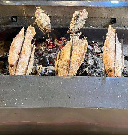 Photo for A photography of a grill with fish and other food cooking on it, rotisserie of fish being cooked on a grill with charcoal. - Royalty Free Image