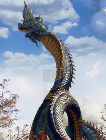 Photo for A photography of a large dragon statue in a park with trees, spiral shaped dragon statue with blue and gold paint on it's head. - Royalty Free Image