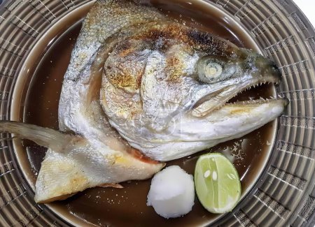 Foto de Una fotografía de un pez con una cuchara y algunas limas, plato de pescado con una lima y una cuña de lima sobre una mesa. - Imagen libre de derechos
