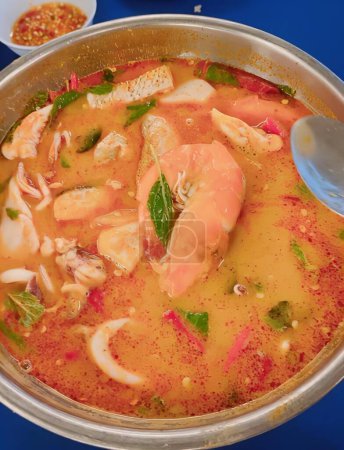 Téléchargez les photos : Photographie d'un bol de soupe aux crevettes et légumes, chaudron de soupe aux crevettes et légumes sur une table bleue. - en image libre de droit