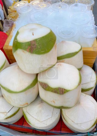 una fotografía de una pila de cocos sentados en la parte superior de una mesa, cocos abuela herrero se apilan en una bandeja en un mercado.