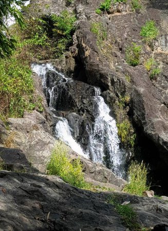 Foto de Una fotografía de una cascada en una zona rocosa con árboles, valle con una cascada y una pequeña cascada en el centro. - Imagen libre de derechos