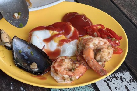 Téléchargez les photos : Une photographie d'une assiette de nourriture avec crevettes, musselling et sauce. - en image libre de droit