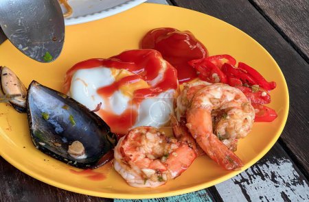 Téléchargez les photos : Une photographie d'une assiette de nourriture avec crevettes, musselling et sauce. - en image libre de droit