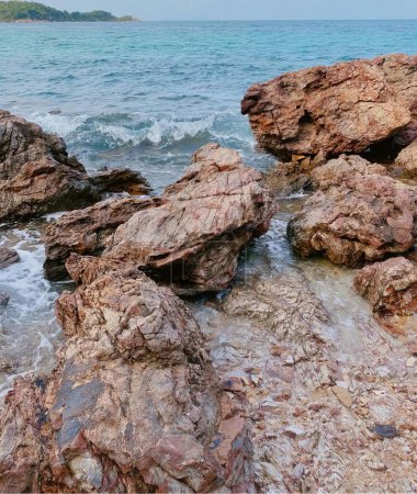 Téléchargez les photos : Une photographie d'une plage rocheuse avec quelques rochers dans l'eau, scène mer-côte avec des rochers et des vagues s'écrasant sur le rivage. - en image libre de droit