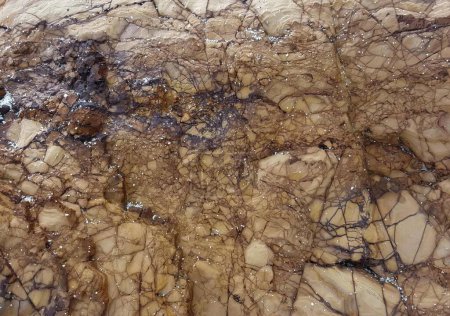 Téléchargez les photos : Une photographie d'un grand rocher avec beaucoup de roches brunes et blanches, rayon électrique d'un avion volant au-dessus d'une surface rocheuse. - en image libre de droit