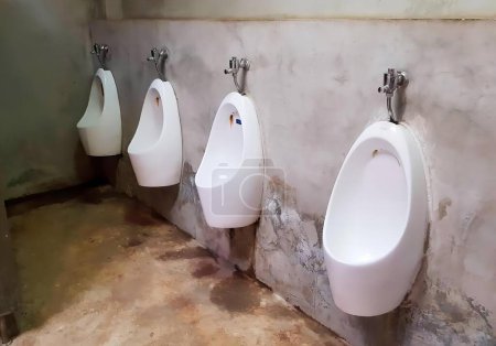 Photo for A photography of a row of urinals in a bathroom with dirty floor, toilet seat and urinals in a bathroom with dirty floor. - Royalty Free Image