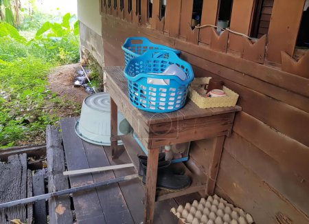 Foto de Una fotografía de una mesa de madera con una cesta de huevos en ella, rueda de alfarero y huevos en una mesa de madera fuera de una casa. - Imagen libre de derechos