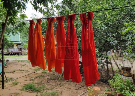 Photo for A photography of a bunch of red shirts hanging on a clothes line, sarongs hanging on a clothes line in a garden. - Royalty Free Image