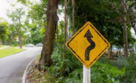 Photo for A photography of a yellow sign with a curved road in the background. - Royalty Free Image