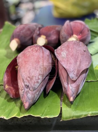 Photo for A photography of a bunch of bananas sitting on a table, banana leaves and a bunch of red bananas on a table. - Royalty Free Image