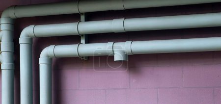 Foto de Una fotografía de una pared rosa con un montón de tubos en ella, tubos de radiador contra una pared rosa con un reloj en la pared. - Imagen libre de derechos