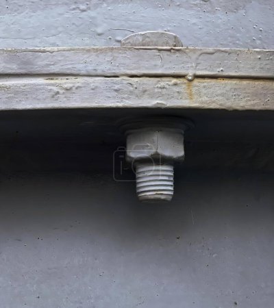Foto de Una fotografía de una tubería que sobresale de una pared con una superficie de cemento, tornillo unido a una pared con un perno en ella. - Imagen libre de derechos
