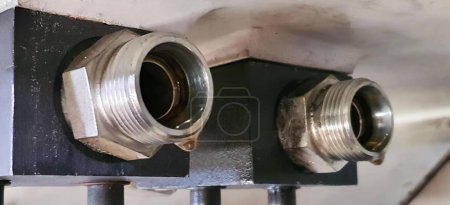 Téléchargez les photos : Une photographie d'un couple de tuyaux métalliques sur un mur, projecteur d'un tuyau métallique avec deux raccords métalliques dessus. - en image libre de droit